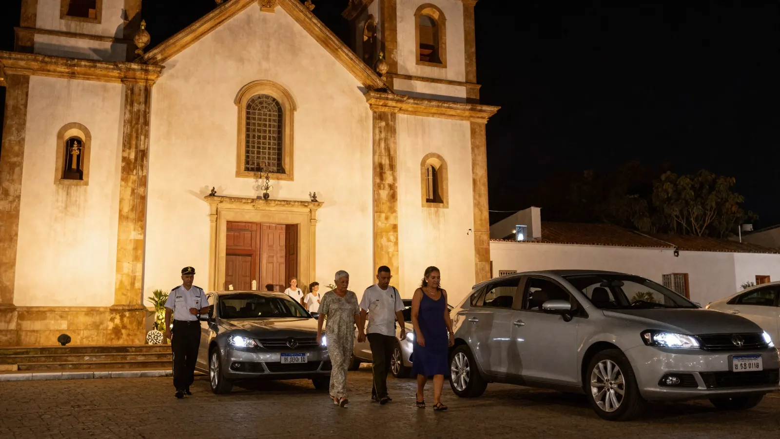 Imagem ilustrativa: organizacao da chegada de carros em frente a igreja iluminada a noite